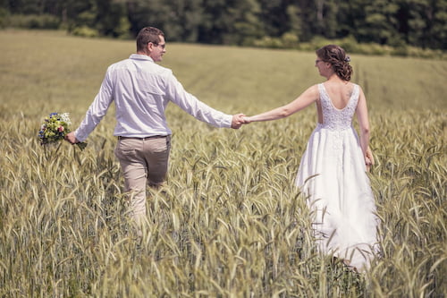 kráčející novomanželský pár v lánu obilí