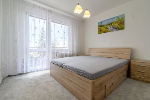 ložnice s dřevěnou manželskou postelí obrazem krajiny a dvěmi stropními světly
